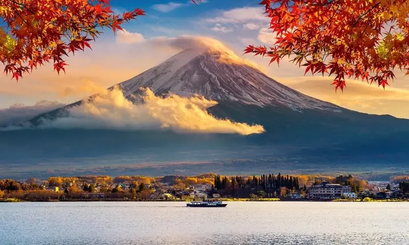 Mount Fuji above a lake, framed by red maple leaves.
