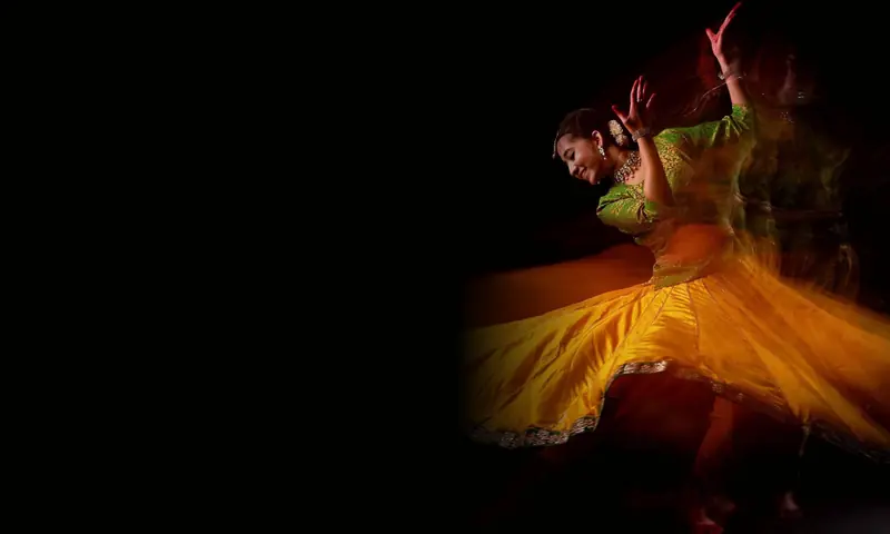 Ishita, the workshop host, mid-spin in a yellow and green Kathak costume.